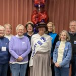 people stand for picture with a costumed women