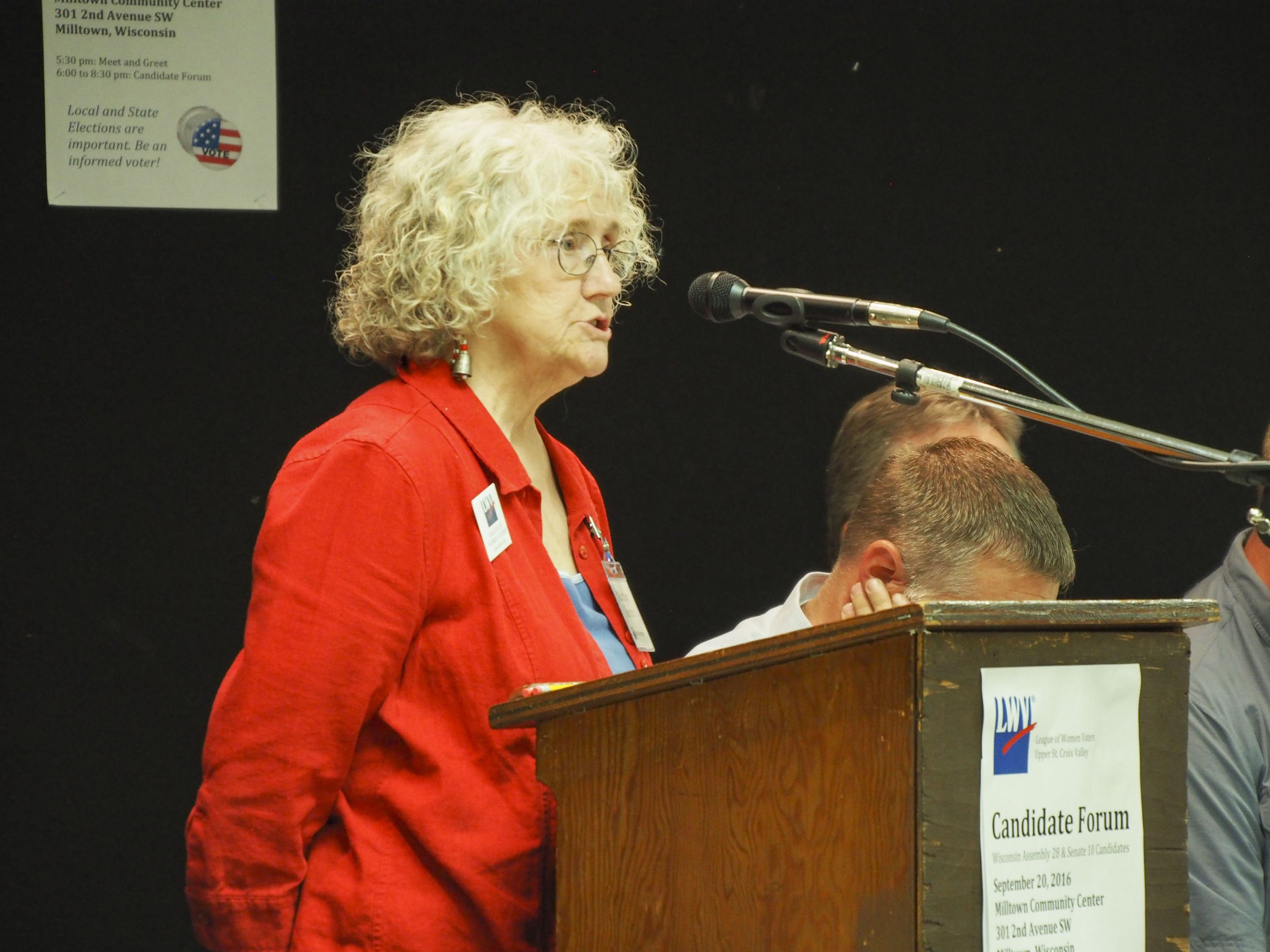A woman stands at a microphone